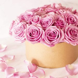 Beautiful floral bouquet with pink roses in a box on a pink background